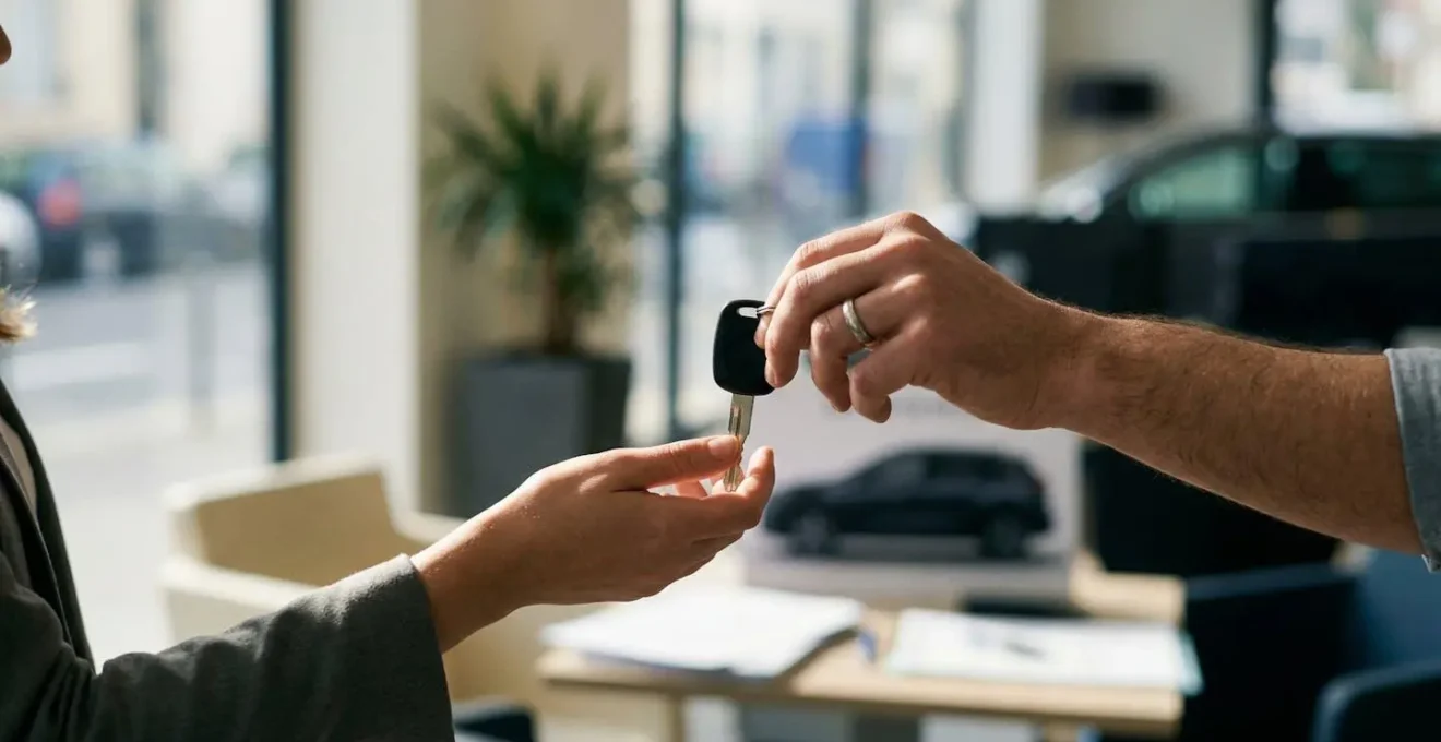 Clés de voiture échangées entre deux mains avec documents d'assurance flous en arrière-plan